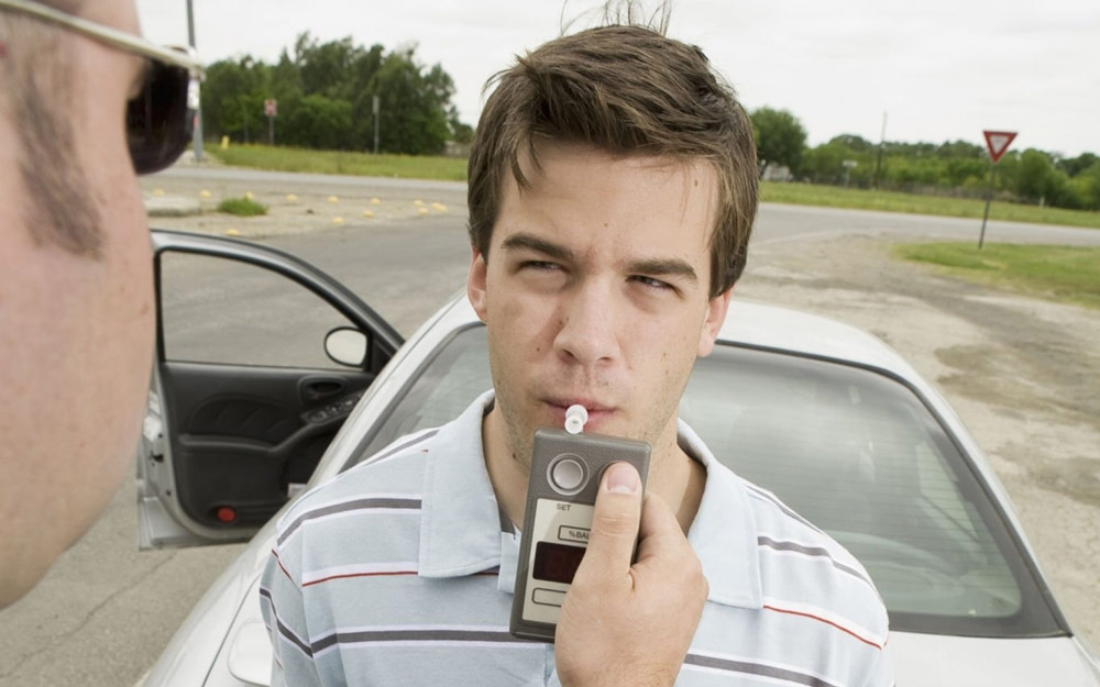 Agente Effettua Alcol Test su Giovane Automobilista Agente Effettua Alcol Test su Giovane Automobilista